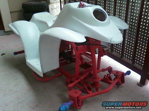 ATV frame with white body panels and red suspension parts