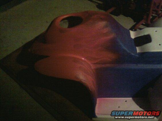 Red and blue plastic car dashboard part with a circular cutout