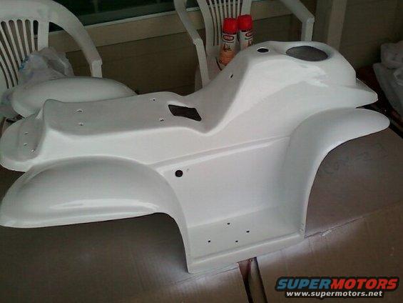 White plastic body panel, possibly for an ATV or similar vehicle, sitting on a cardboard surface