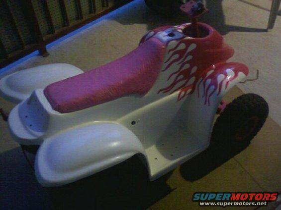 White toy ATV with pink seat and red flame decals, right front wheel visible