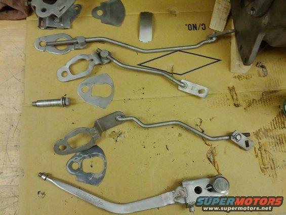 Metal linkage parts and gaskets laid out on a cardboard surface