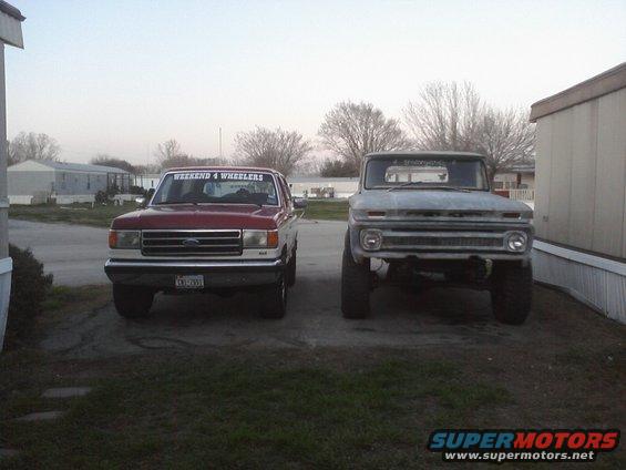 1989 Ford Bronco and a lifted older model truck parked outside