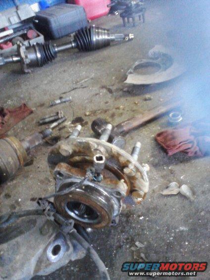 Dismantled vehicle hub and axle components on garage floor