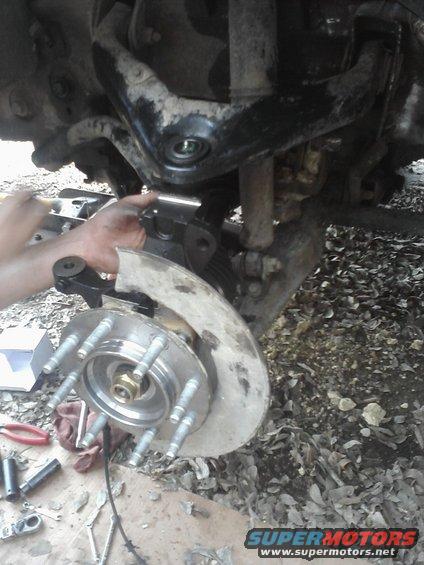 Front wheel hub and suspension components being worked on, with tools nearby