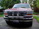 1993 Ford Bronco - A maroon Ford Bronco with a chrome bull bar and fog lights is parked on a driveway.