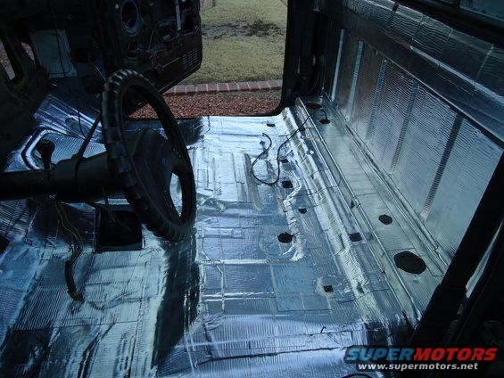 Interior of a truck with sound deadening material on the floor and walls, showing the steering wheel and gear shift
