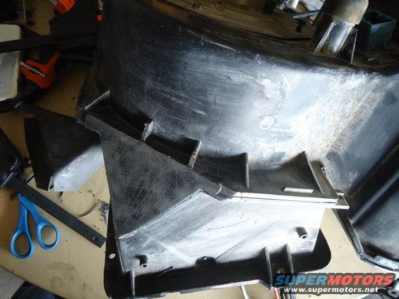 Black plastic automotive part with internal fins, showing scratches and scuffs