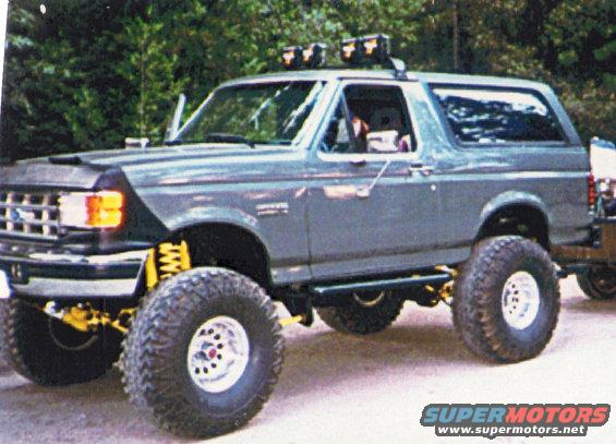 Lifted gray 1988 Ford Bronco with off-road tires and roof-mounted light bar
