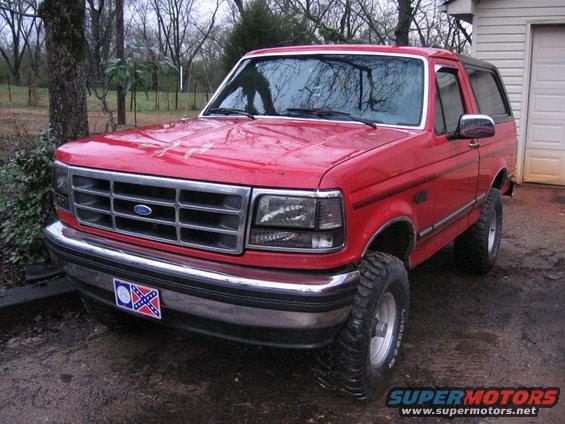 1993 Ford Bronco with aftermarket wheels and tires parked in a muddy yard