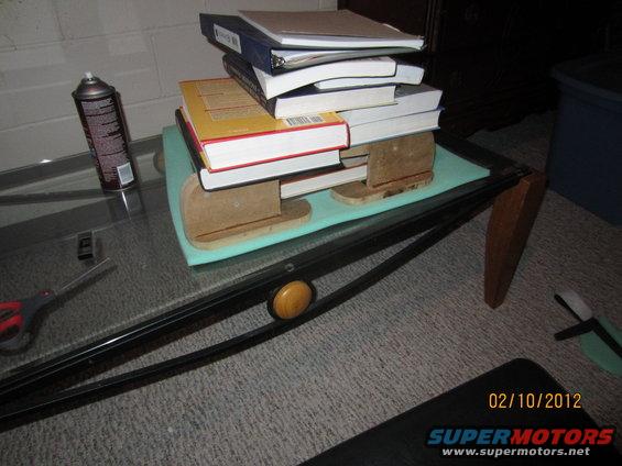 Stack of books on a glass-top table with a spray can and scissors nearby