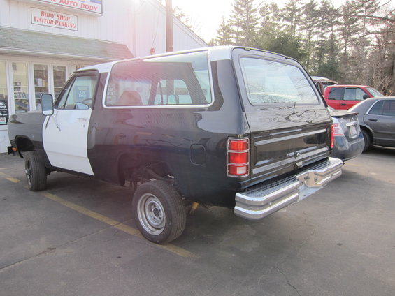 Two-tone Dodge Ramcharger with black rear and white front, parked outside a body shop