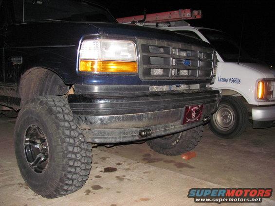 1994 Ford Bronco front end with large tires, parked next to a white van with license #56538