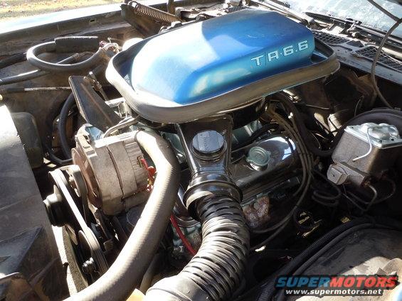 Engine bay showing blue air cleaner lid with "TA 6.6" text, alternator, and hoses