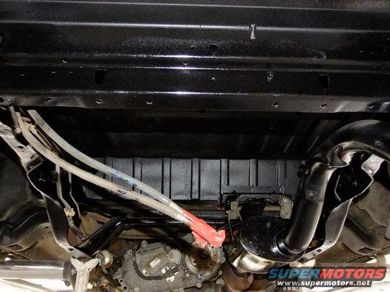 Underside of a vehicle with black painted frame, exhaust pipe, and transmission components