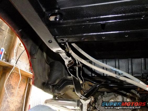 Undercarriage view of a vehicle with black painted frame and fuel lines