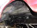 1995 Ford Bronco - Close-up view of the rear chassis and wheel well of a red vehicle, highlighting the undercoating.