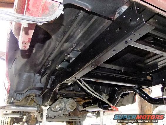 Red 1995 Ford Bronco rear chassis underside, showing frame, exhaust, and transfer case