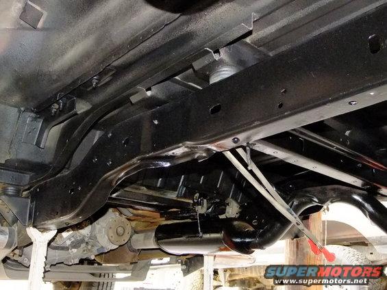 Undercarriage of a 1990s Ford Bronco showing frame, exhaust, and drivetrain components