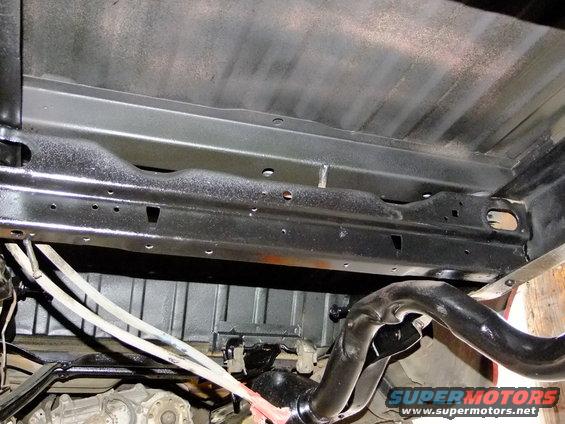 Underside of a vehicle chassis with exhaust pipe and suspension components visible
