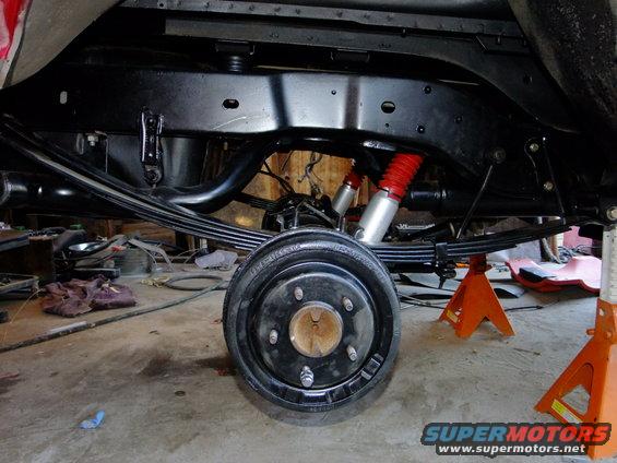 Rear axle with drum brake, leaf springs, and red shock absorbers on jack stands