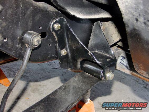 Close-up of a black metal bracket attached to a vehicle's frame, with a sway bar link visible