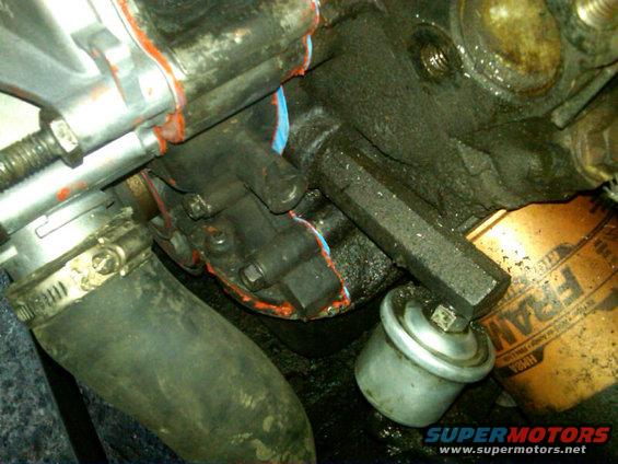 The last picture shows a closeup of this section.  The silver thingy is the Oil pressure switch, no idea what goes into the threaded open part on the Timing Cover next to it though.