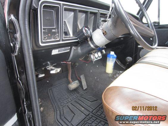 Vehicle interior with black dashboard, tan and brown seats, and a black steering wheel. A shaker bottle is on the passenger side