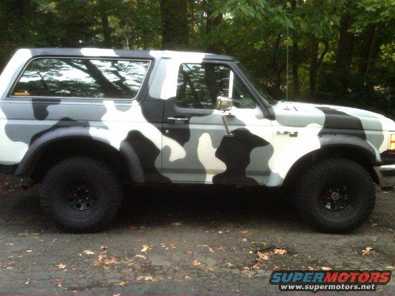 Camouflaged Ford Bronco, side view, with black wheels and aftermarket fender flares
