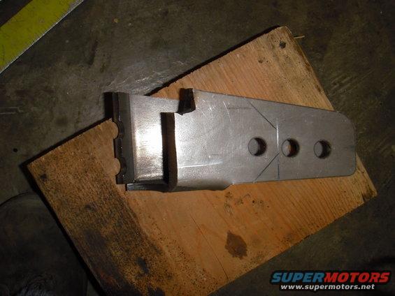 Metal bracket with three holes and scribe lines, resting on wood