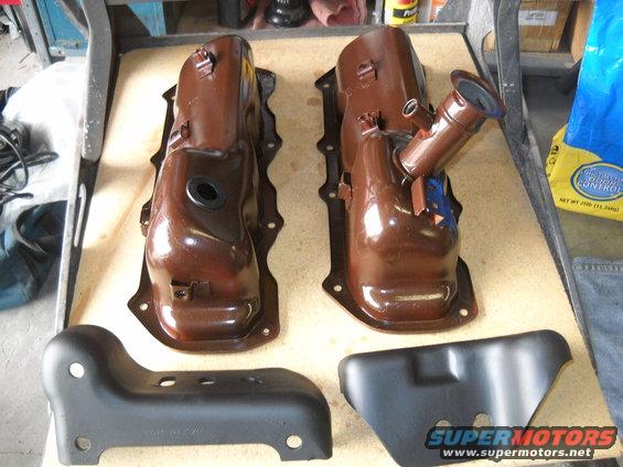 Two brown painted engine valve covers and two black metal brackets on a table