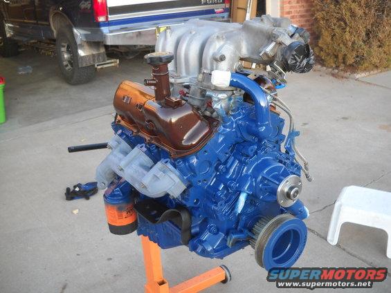 Blue engine on an orange stand with a Ford truck in the background