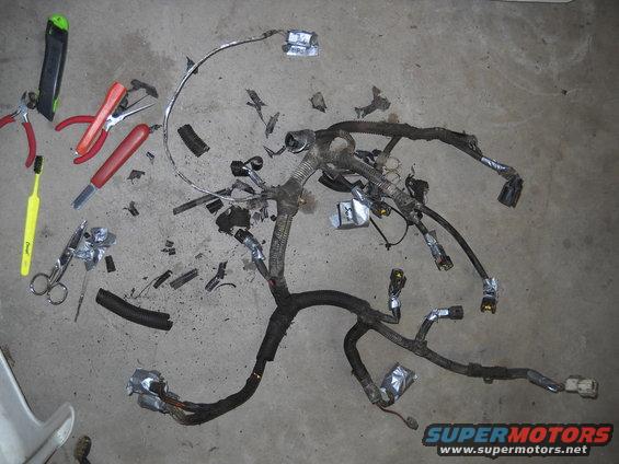 Vehicle wiring harness spread on concrete floor with tools