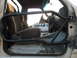 1991 Ford Bronco - The interior of a vehicle shows a roll cage and seats, with a white van in the background.