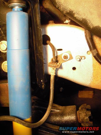 Close-up of a blue shock absorber and brake line on a vehicle frame