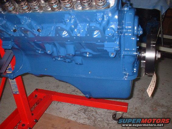 Blue V8 engine block on a red engine stand, showing the front and side of the block with valve springs visible