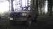 1995 Ford Bronco - This muddy Ford Bronco is parked in a wooded area with sunlight filtering through the trees.