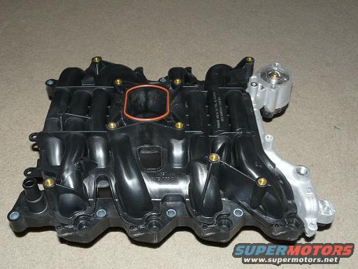 Engine intake manifold with orange gasket visible. Text and Supermotors logo on the bottom right