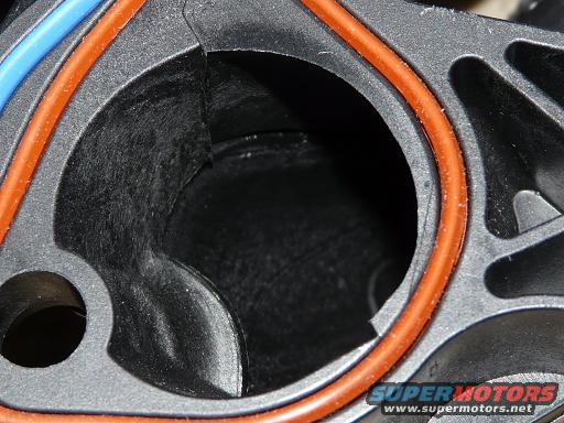Close-up of a black plastic intake manifold part with orange and blue seals