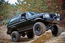 Black Ford Bronco with lifted suspension and off-road tires climbing rocks