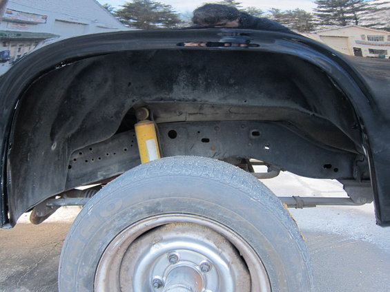 Close-up of a vehicle's rear wheel well, showing the tire, suspension, and frame