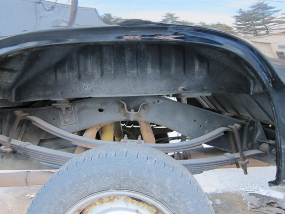 Rear wheel well and suspension of a truck, showing leaf springs and part of the tire
