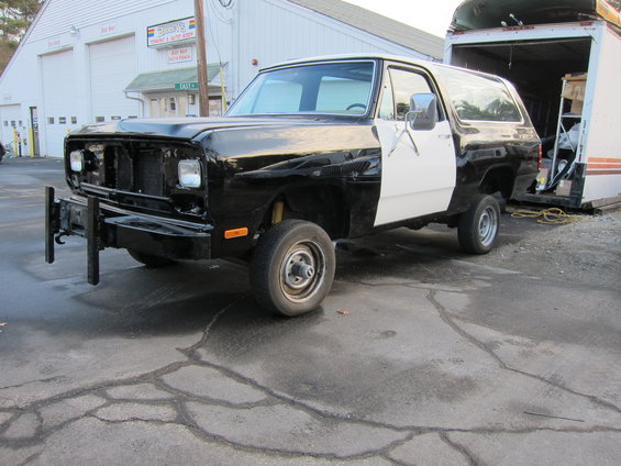 Black and white SUV with a push bumper and missing grille, parked in front of a building