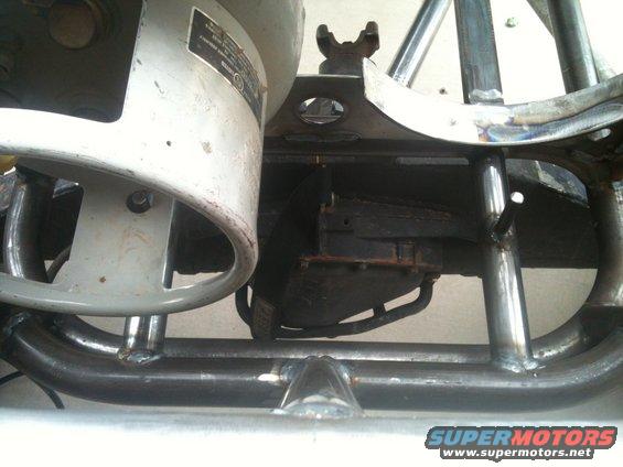 Close-up of custom roll cage tubing and suspension parts, with a label on a grey component