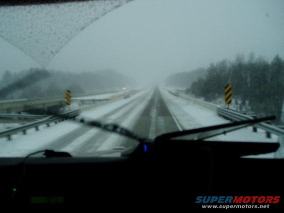 Driving on a highway covered in snow with low visibility