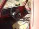 1993 Ford Bronco - The interior of a red truck cab, a worn plaid seat and a dashboard with a radio and steering wheel.