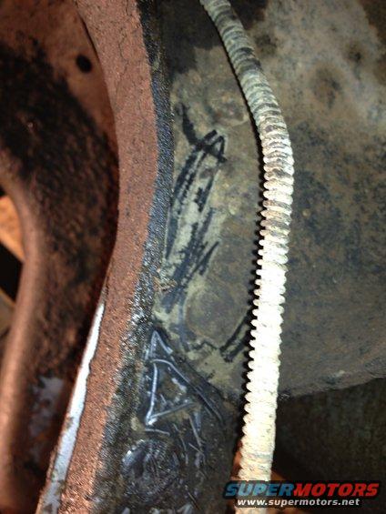 Close-up of a rusty metal part with black markings and a ribbed hose attached