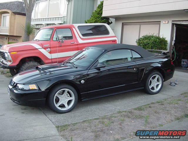 Black convertible Mustang parked next to a red Ford Bronco