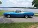 1973 Ford Ranchero - A blue 1973 Ford Ranchero sits parked on a paved surface next to a large body of water.