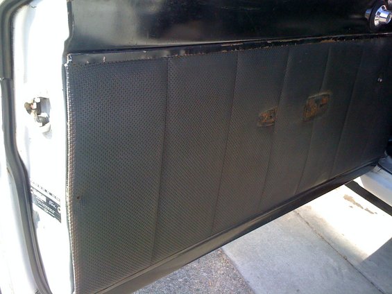 Interior door panel with perforated vinyl and two faded emblems
