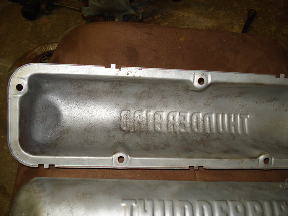 Two aluminum engine valve covers, one with embossed text 'THUNDERBIRD'